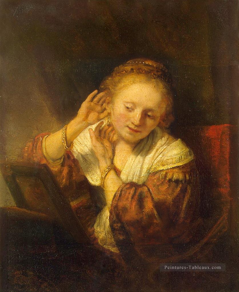 Jeune femme essayant des boucles d’oreilles Rembrandt Peintures à l'huile